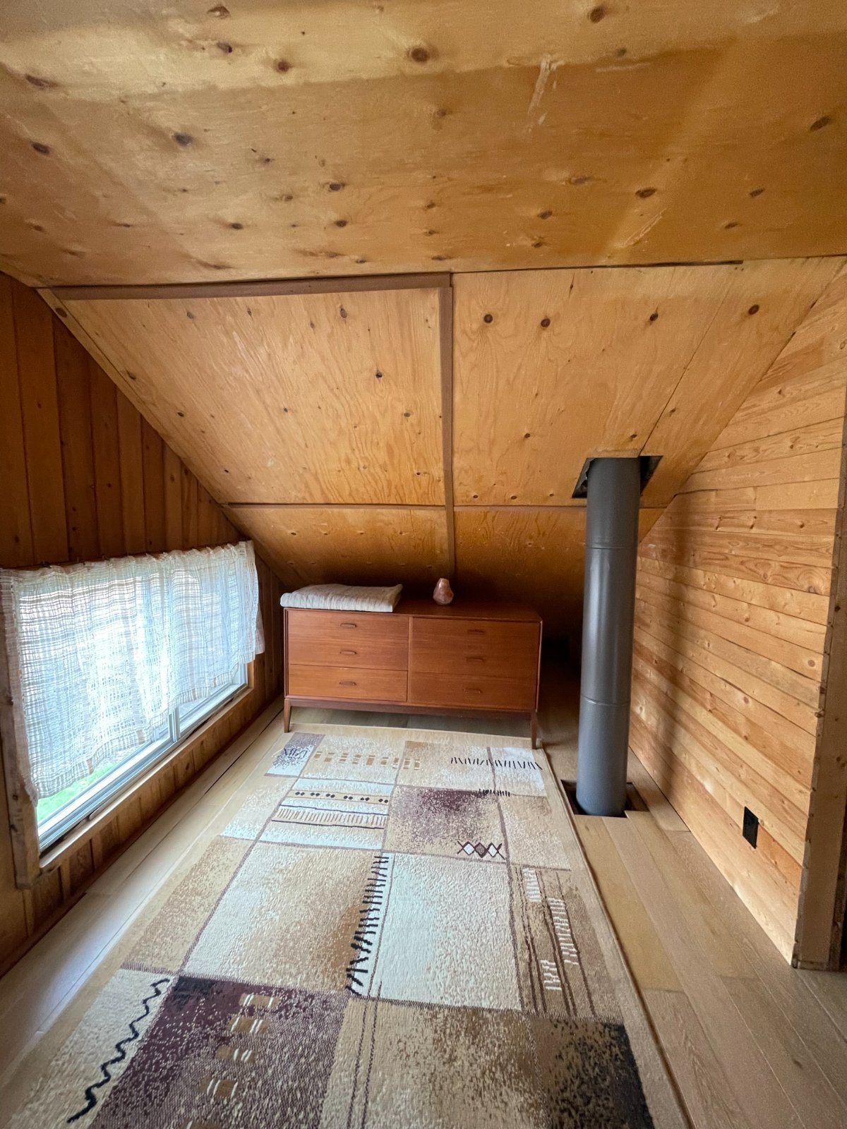 A mid-century dresser beneath the window in the bedroom