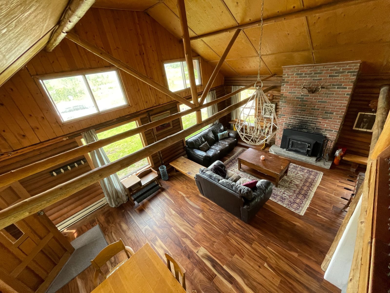Living room with brick fireplace and vaulted wood ceiling, seen from the loft