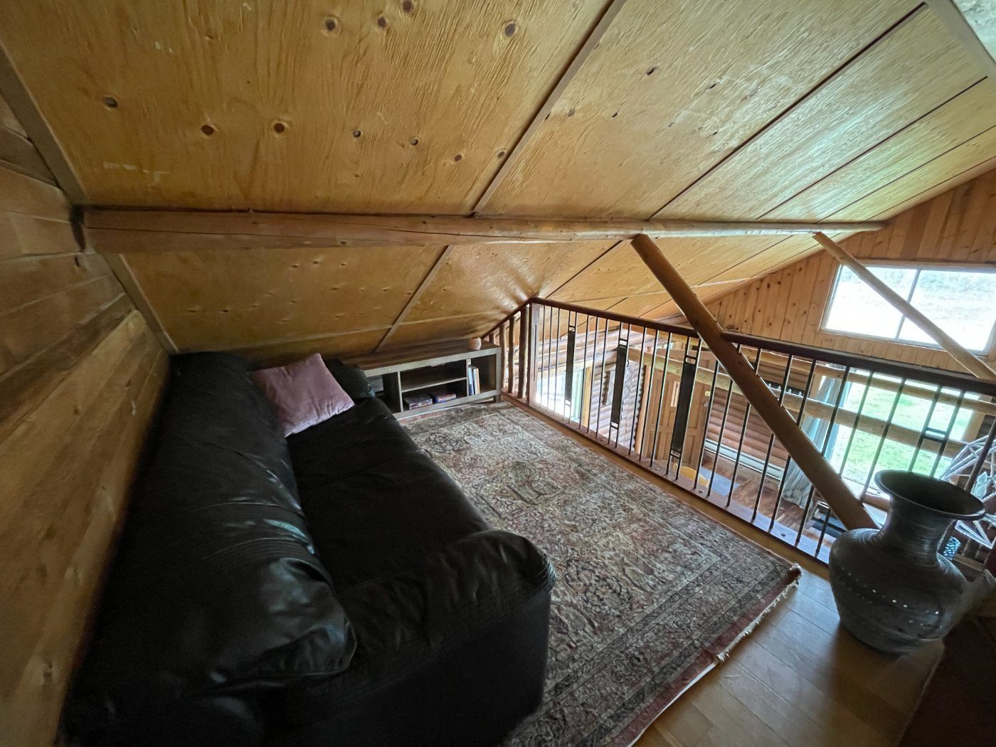 The loft sitting area with a leather sofa under the sloped ceiling, overlooking the great room